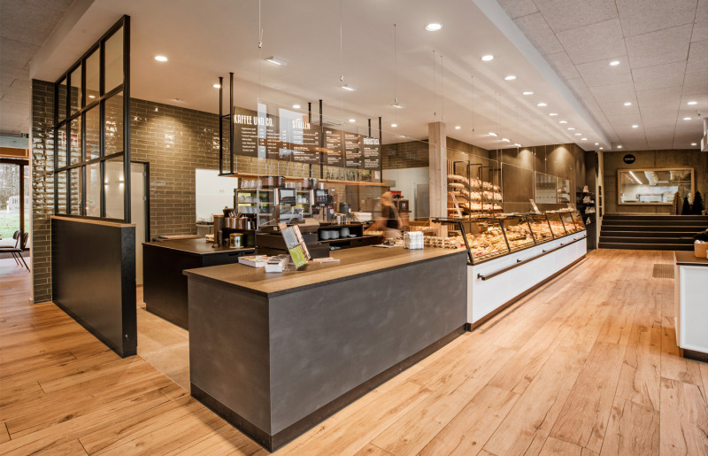Kompletter Ladenausbau für eine moderne Bäckerei mit maßgefertigter Einrichtung inklusive Verkaufstheke und einem Raumteiler im Industrie-Stil.